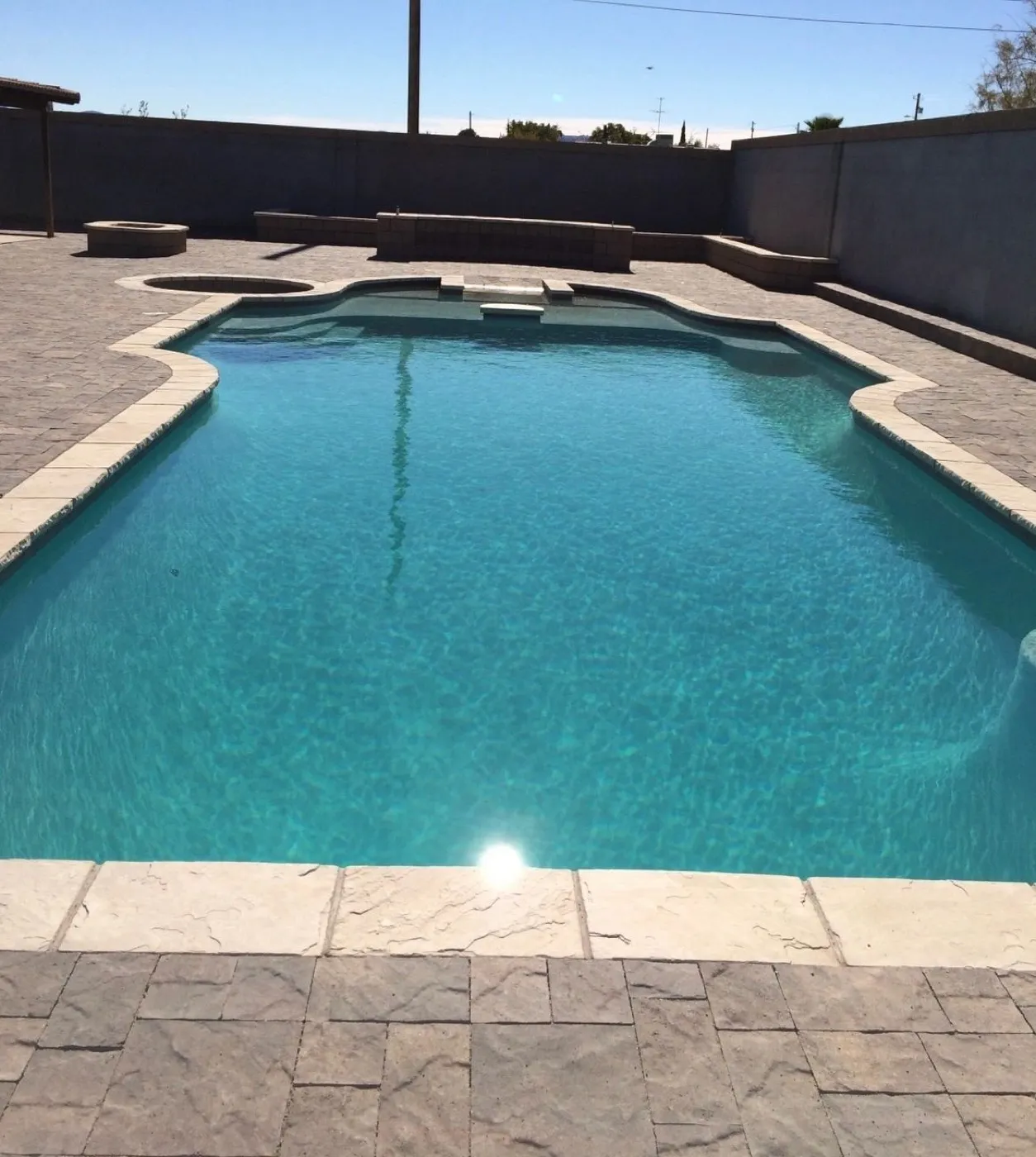Concrete pool deck around a backyard pool